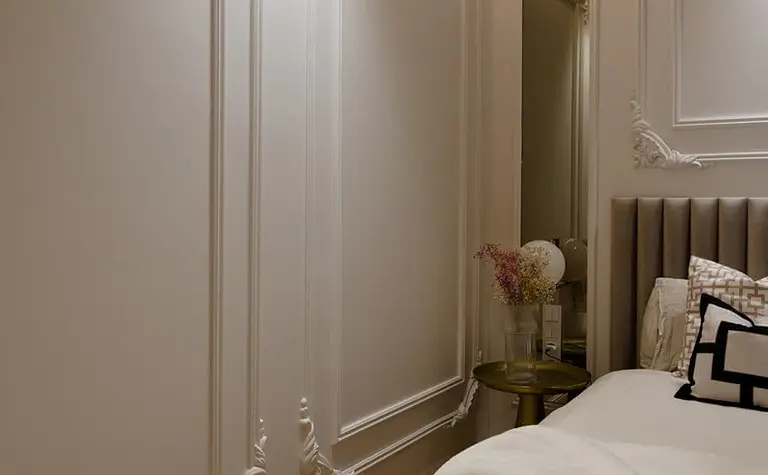 Wnętrze sypialni z jasnymi ścianami, drewnianą podłogą i eleganckimi detalami.