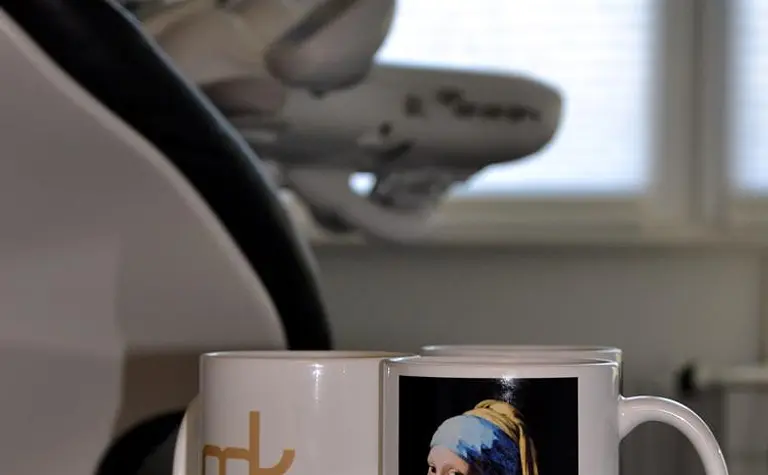 Biuro z filiżankami na szklanym stole, minimalistyczny styl, nowoczesne wnętrze.