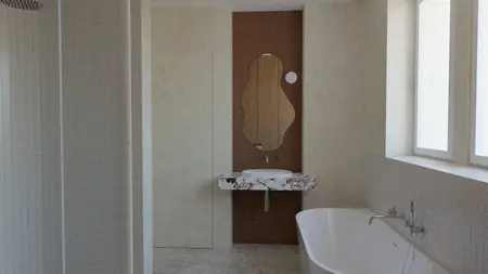 Wnętrze łazienki w stylu minimalistycznym z marmurową umywalką i wanną.