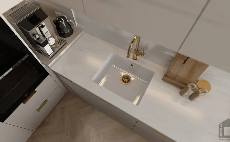 Kuchnia z białymi meblami, złotym kranem i akcesoriami.