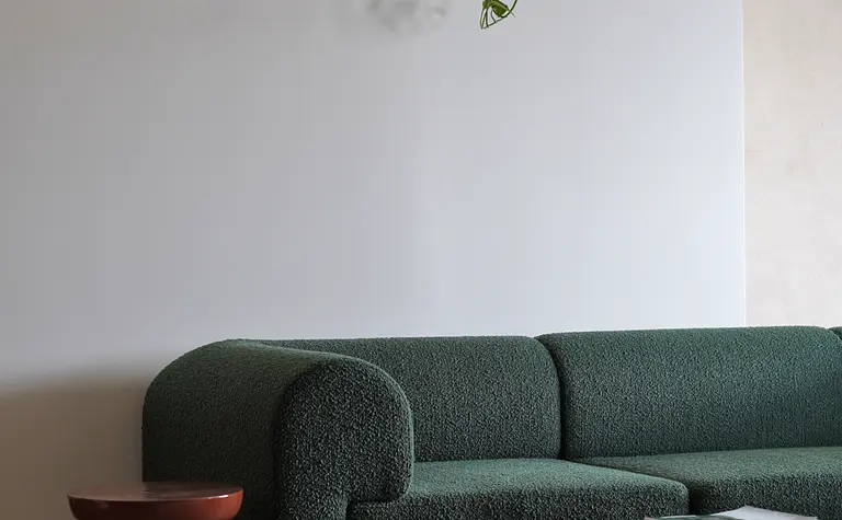 Salon z zieloną sofą, szklanym stolikiem i rośliną w doniczce, nowoczesny design.