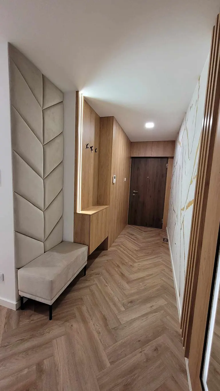 Przedpokój z nowoczesnym designem, drewnianą podłogą i eleganckimi detalami.
