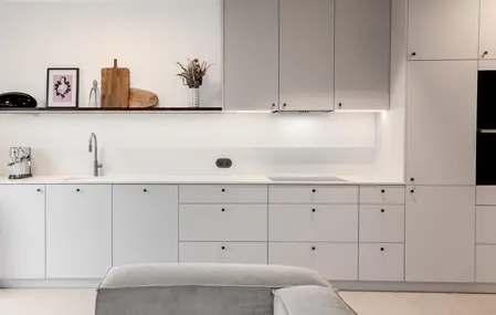 Wnętrze kuchni z szarymi meblami, białym blatem i akcentami boho, art deco i eklektycznymi.