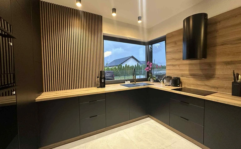 Kuchnia w stylu industrialnym z czarnymi meblami i drewnianymi detalami.
