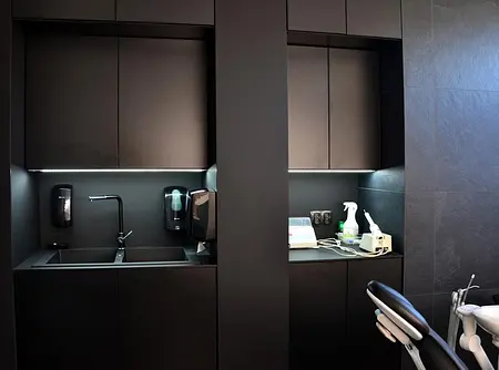 Wnętrze minimalistycznej kuchni z czarnymi meblami, umywalką i akcesoriami.