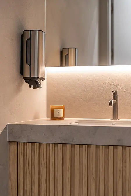 Minimalistyczna łazienka z drewnianą szafką, umywalką i eleganckim kranem.