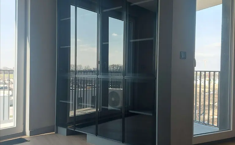 Garderoba z dużą szafą w stylu industrialnym i naturalnym oświetleniem.