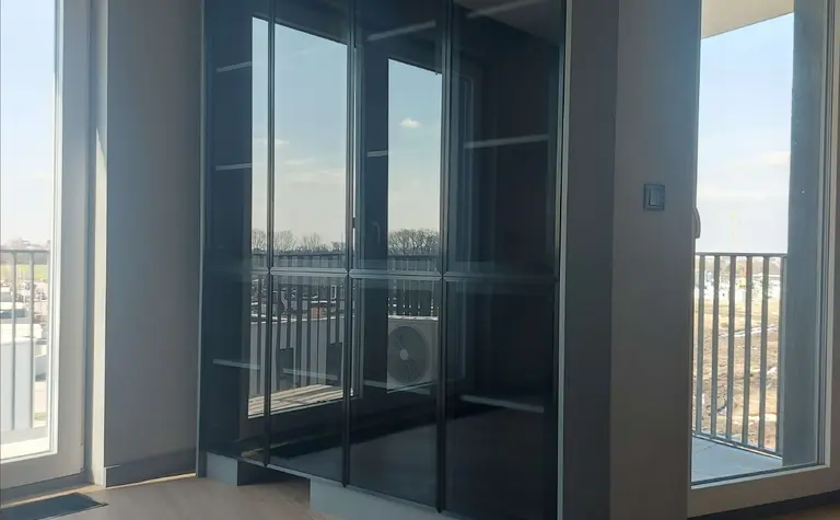 Garderoba z dużą szafą w stylu industrialnym i naturalnym oświetleniem.
