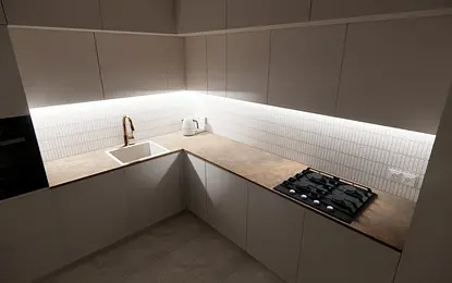 Nowoczesna kuchnia z białymi meblami, brązowym blatem i minimalistycznymi akcentami.