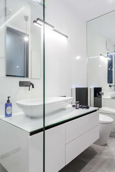 Nowoczesna łazienka z białą umywalką i czarnymi detalami, minimalistyczny design.