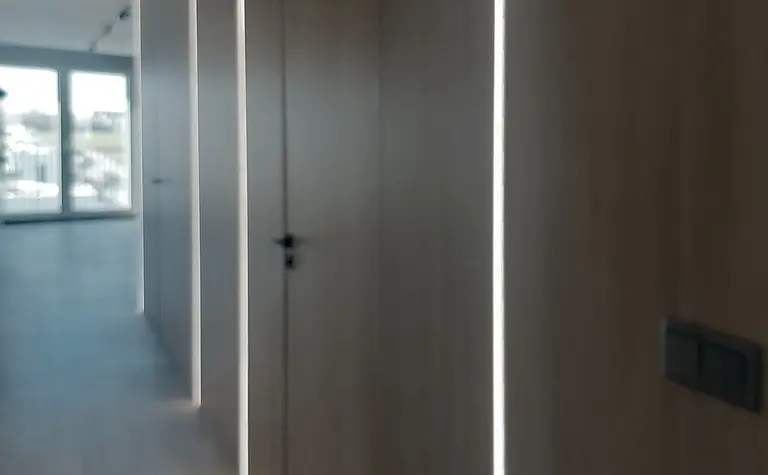 Korytarz w stylu industrialnym z drewnianymi ścianami i nowoczesnym oświetleniem LED.