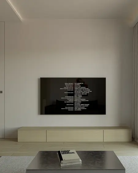 Minimalistyczny salon z nowoczesnym telewizorem i drewnianymi meblami.
