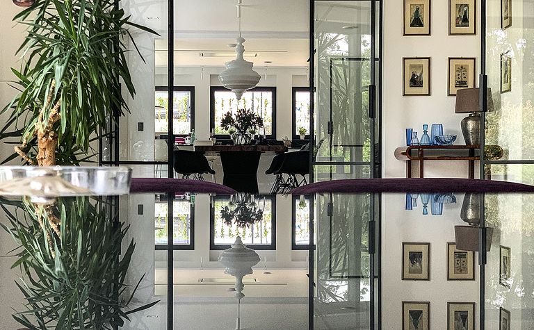 Wnętrze minimalistyczne z rośliną, szklanym stołem i elementami minimaluxe oraz quiet luxury.