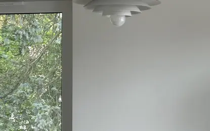 Lampka sufitowa w minimalistycznym wnętrzu z białymi ścianami i dużym oknem.