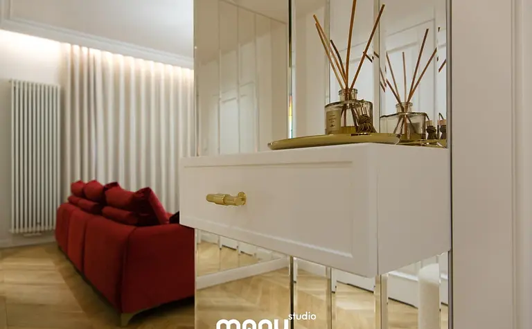 Nowoczesny salon z czerwonymi meblami, białą komodą i dekoracjami.