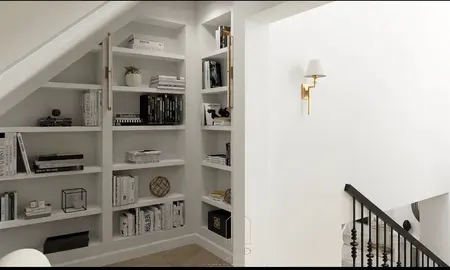 Wnętrze z białymi półkami, książkami i złotymi akcentami, nowoczesny design.