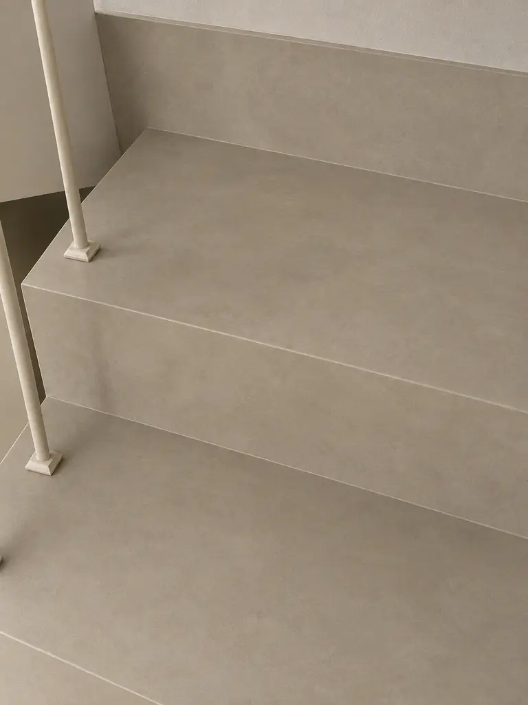 Beżowe schody z białymi balustradami w stylu art deco, industrialnym i minimalistycznym.