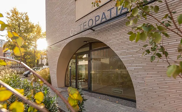 Wnętrze biura z dużymi oknami, minimalistycznym wystrojem i roślinami.
