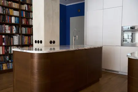 Eklektyczna kuchnia z brązowym blatem, białymi meblami i niebieską ścianą.