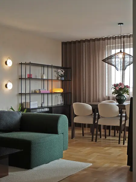 Wnętrze jadalni z zieloną sofą, drewnianym stołem i nowoczesnymi lampami.