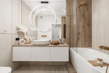 Współczesna łazienka z białą umywalką, drewnianymi detalami i oświetleniem LED.