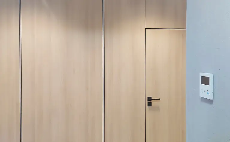 Wnętrze z industrialnym stylem, drewniane drzwi i szare ściany.