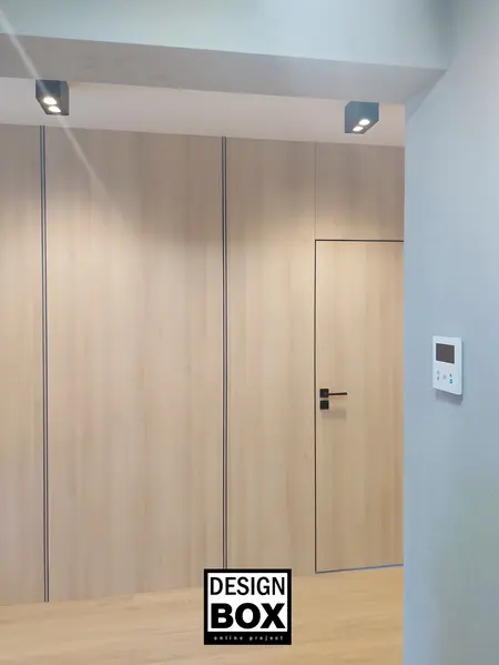 Wnętrze z industrialnym stylem, drewniane drzwi i szare ściany.