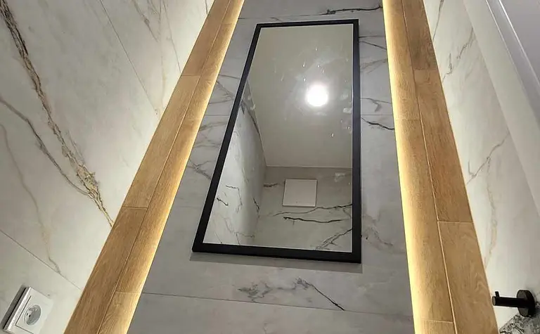 Wnętrze łazienki z marmurowymi ścianami i drewnem, minimalistyczny design.