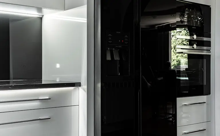 Nowoczesna kuchnia z białymi meblami i czarnymi akcentami, minimalistyczny design.