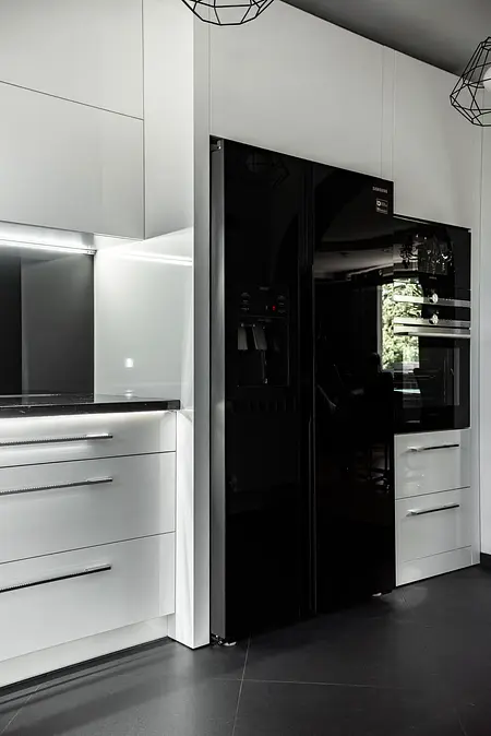 Nowoczesna kuchnia z białymi meblami i czarnymi akcentami, minimalistyczny design.