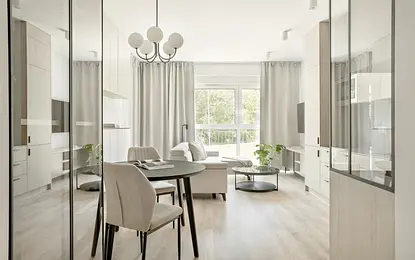 Wnętrze nowoczesnego salonu z minimalistycznym designem, jasnymi meblami i roślinnością.
