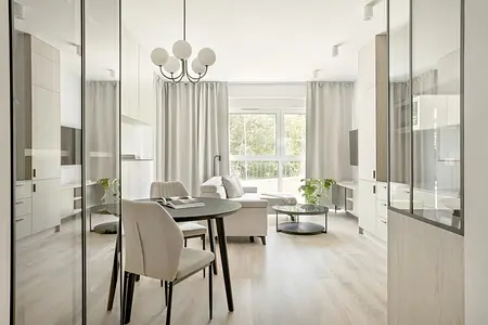 Wnętrze nowoczesnego salonu z minimalistycznym designem, jasnymi meblami i roślinnością.