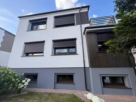 Widok na nowoczesną fasadę budynku z oknami i drewnianymi akcentami w stylu tradycyjnym.