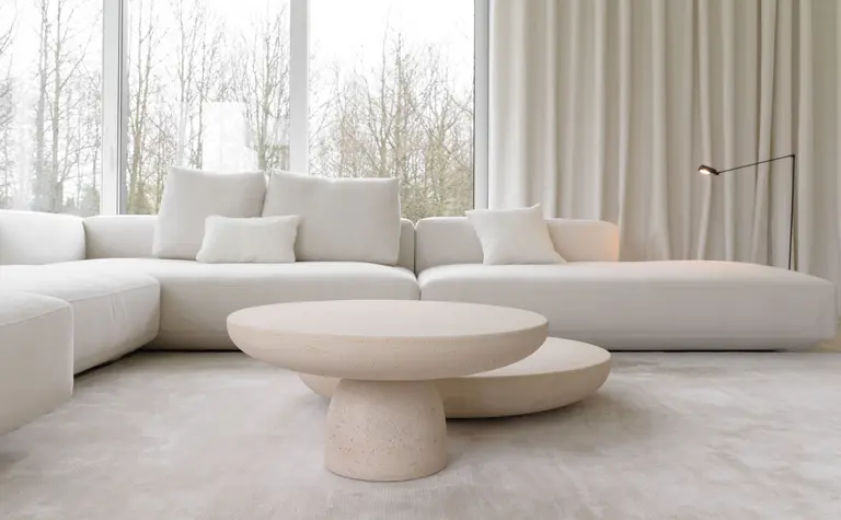 Minimalistyczny salon z białą sofą i okrągłym stolikiem w stylu minimaluxe