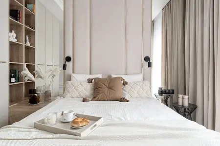 Współczesna sypialnia z jasnym łóżkiem, poduszkami i dekoracjami.