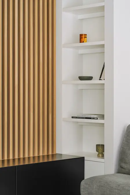 Wnętrze z drewnianą ścianką, białymi półkami i minimalistycznym designem.