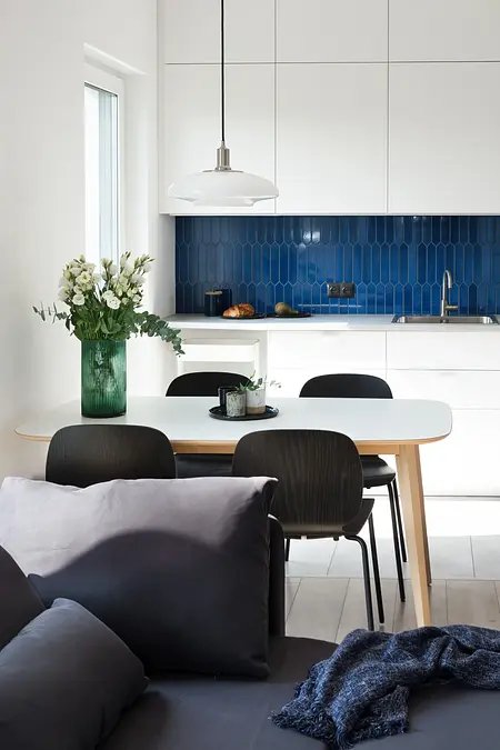 Kuchnia minimalistyczna z białymi meblami i skandynawską stylistyką, niebieska ściana.