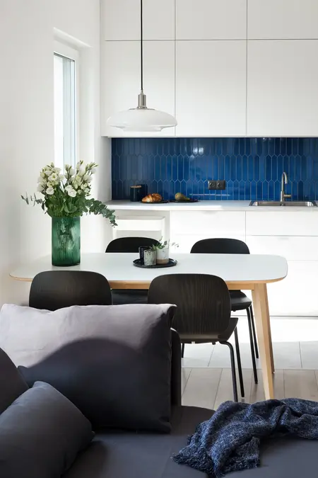 Kuchnia minimalistyczna z białymi meblami i skandynawską stylistyką, niebieska ściana.