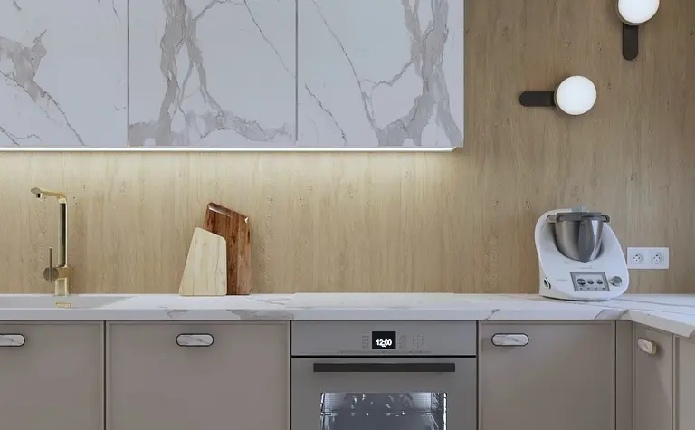 Kuchnia z beżowymi meblami, białym blatem i nowoczesnym oświetleniem.