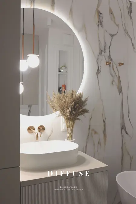 Nowoczesna łazienka z okrągłym lustrem, minimalistycznym designem i akcentami boho.