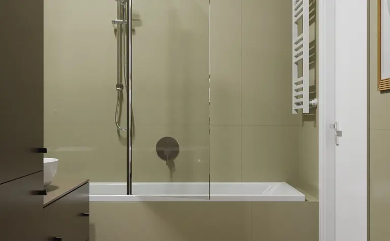 Nowoczesna łazienka z wanną, ciemnymi meblami i minimalistycznym designem.