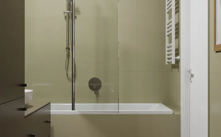 Nowoczesna łazienka z wanną, ciemnymi meblami i minimalistycznym designem.