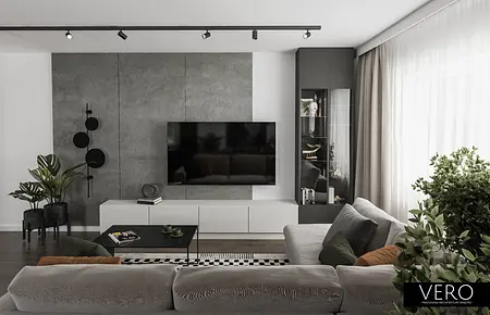 Minimalistyczny salon z zielonymi roślinami i szarymi meblami.