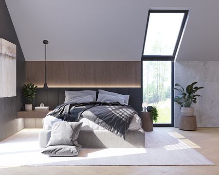 Wnętrze sypialni z szarym łóżkiem, drewnianymi detalami i dużymi oknami, minimalistyczny styl.