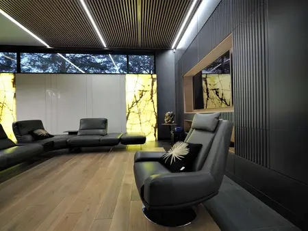 Nowoczesny salon z czarnymi meblami i drewnianą podłogą, z dużymi oknami.