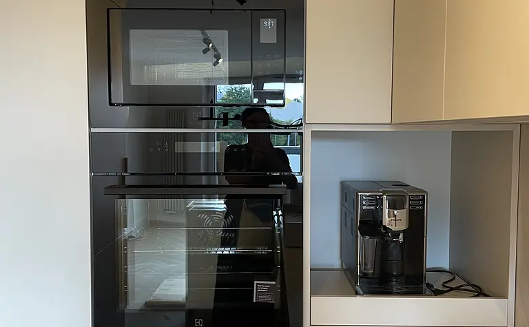 Nowoczesna kuchnia z białymi meblami, czarnym piekarnikiem, industrialnym blatem.