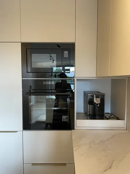 Nowoczesna kuchnia z białymi meblami, czarnym piekarnikiem, industrialnym blatem.