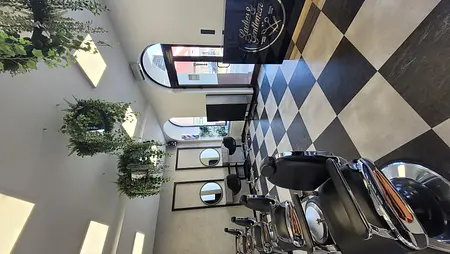 Wnętrze salonu fryzjerskiego z czarnymi fotelami i roślinami w stylu industrialnym i nowoczesnym.