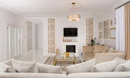 Wnętrze salonu w stylu glamour i quiet luxury z beżową sofą i ozdobnymi ścianami.