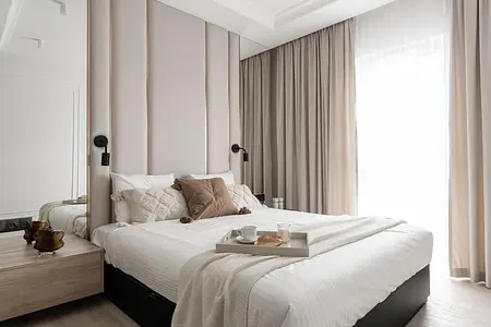 Współczesna sypialnia z jasnymi zasłonami i komfortowym łóżkiem.